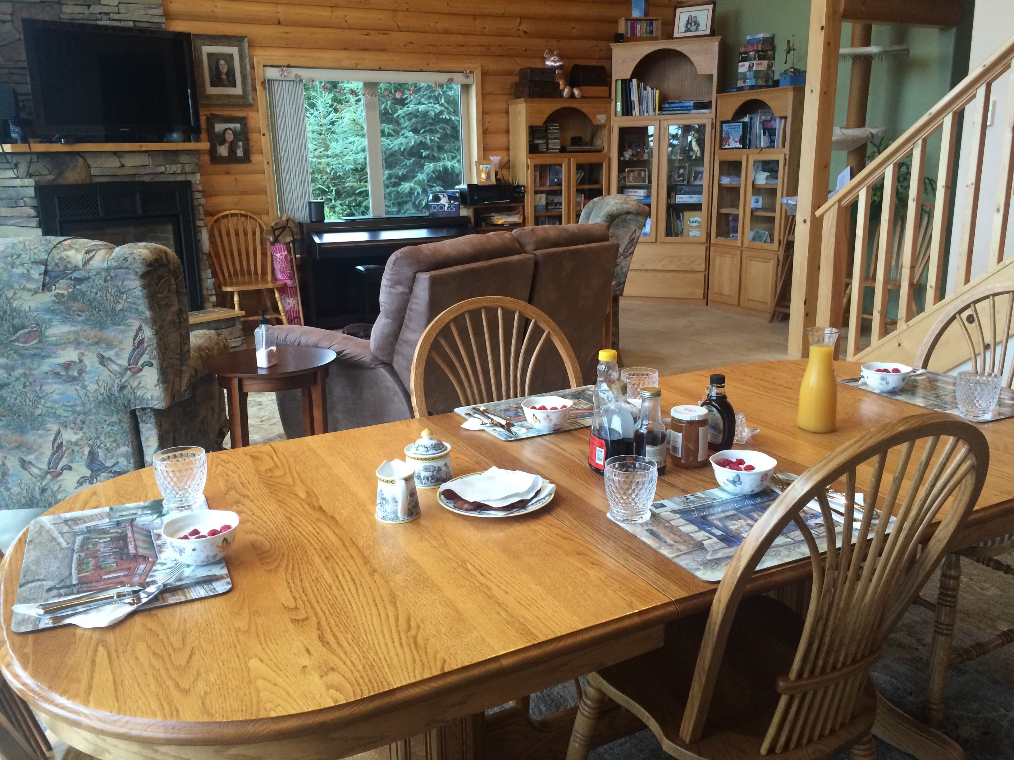 Large dining table in foreground with comfortable chairs, fireplace, and wall-mounted TV in backgroundTV